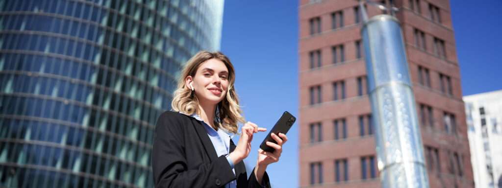 low angle shot businesswoman standing street sunny day holding smartphone using app 1